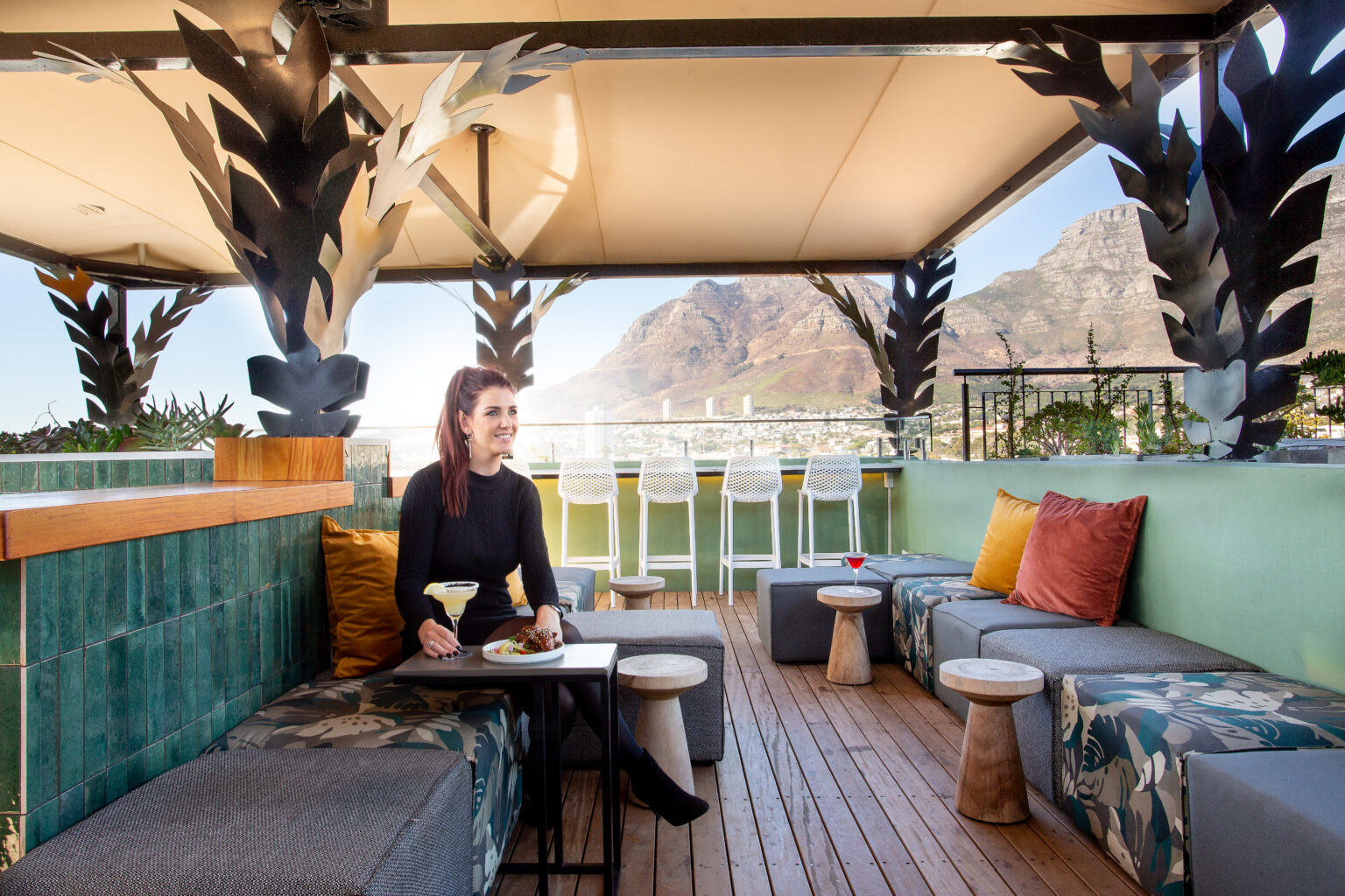 A patron enjoying a drink on her own, with Devils Peak mountain in the background