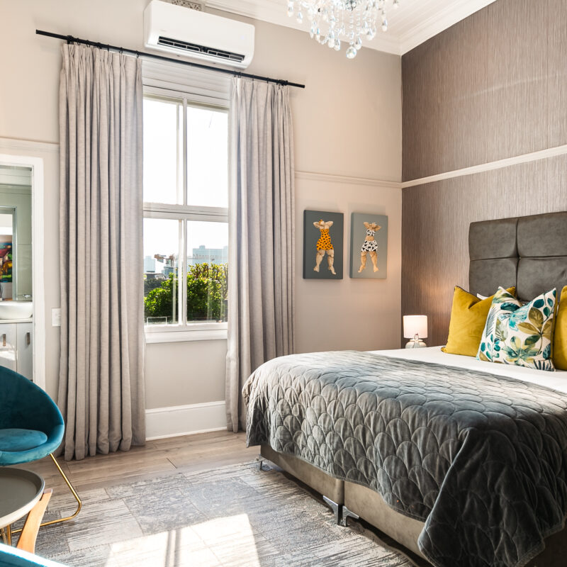 An elegant boutique hotel bedroom featuring a queen-size bed adorned with a dark grey quilted bedspread.